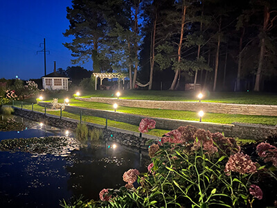 Valgustitega terrassiline tiigi kallas.